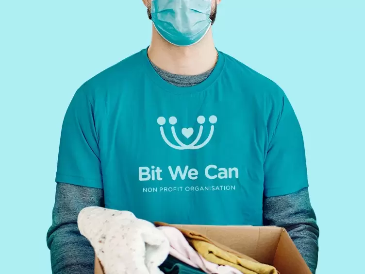 A man wearing a mask holding a box of clothes that bit.