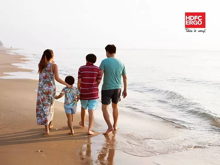 A family walking on a beach with a red HDFC Ergo banner.