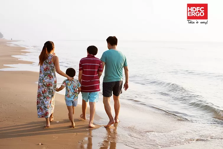 A family walking on a beach with a red HDFC Ergo banner.