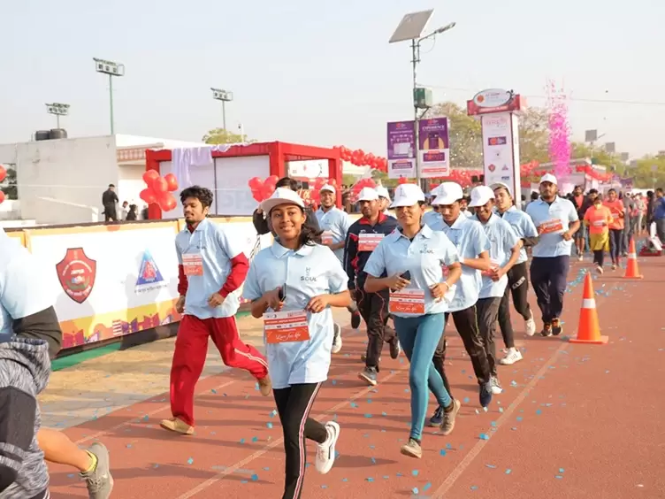 Participants in the Jaipur Marathon racing around the track in their blue shirts.