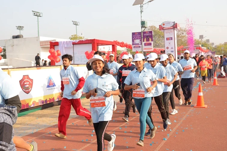 Participants in the Jaipur Marathon racing around the track in their blue shirts.